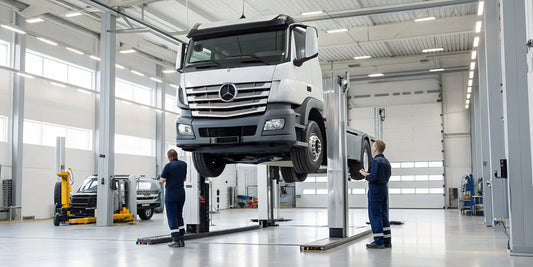 A professional mechanic performing a diesel truck service on a vehicle lifted in a garage.