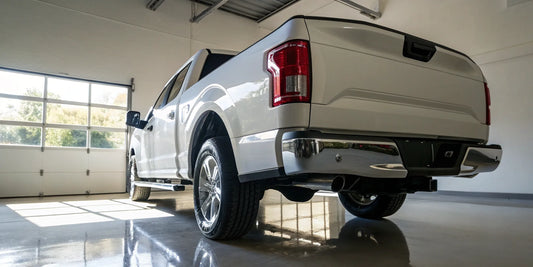 A white truck's rear bumper in an auto shop, a key component of the total replacement cost.