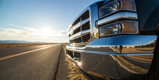 A heavy-duty chrome truck bumper for sale on a pickup driving on an open road.