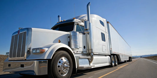 A white semi truck on the highway, a result of a proper preventive maintenance plan.